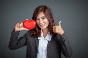 Asian businesswoman smile thumbs up with red heart on gray background